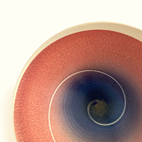 Tapered porcelain bowl with ivory exterior and spiral center design glazed in pink/orange and blue/purple by Wayne Bates at Cottage Curator - Sperryville VA Art Gallery